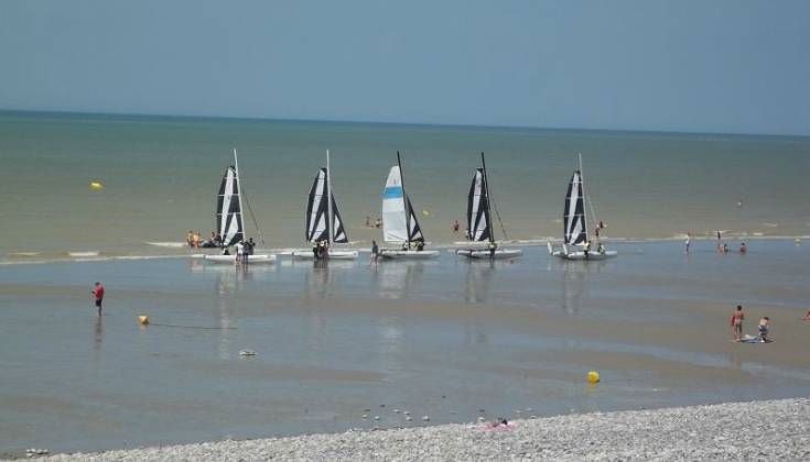 Voiliers sur une plage ensoleillée et calme.