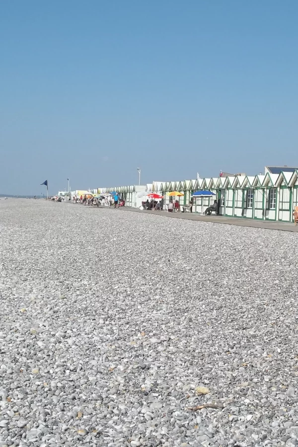 Plage avec cabanes colorées et galets.
