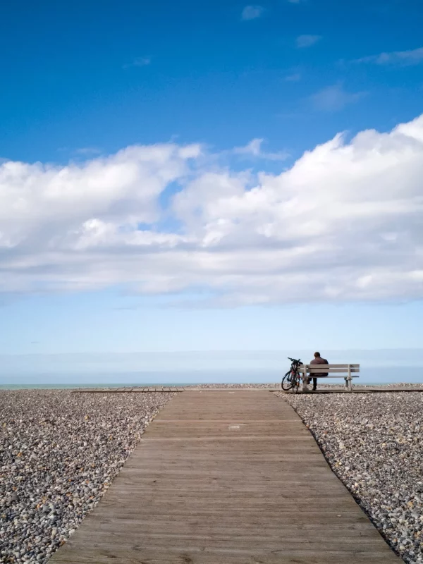 Un homme assis sur un banc au bord de la mer.