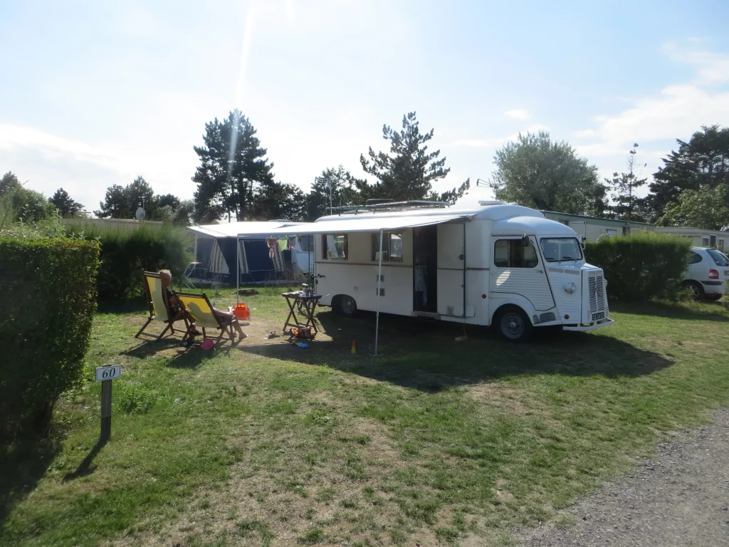 Camping avec une caravane et des chaises longues.