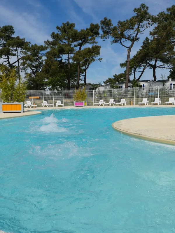 Piscine entourée de chaises longues et de arbres.