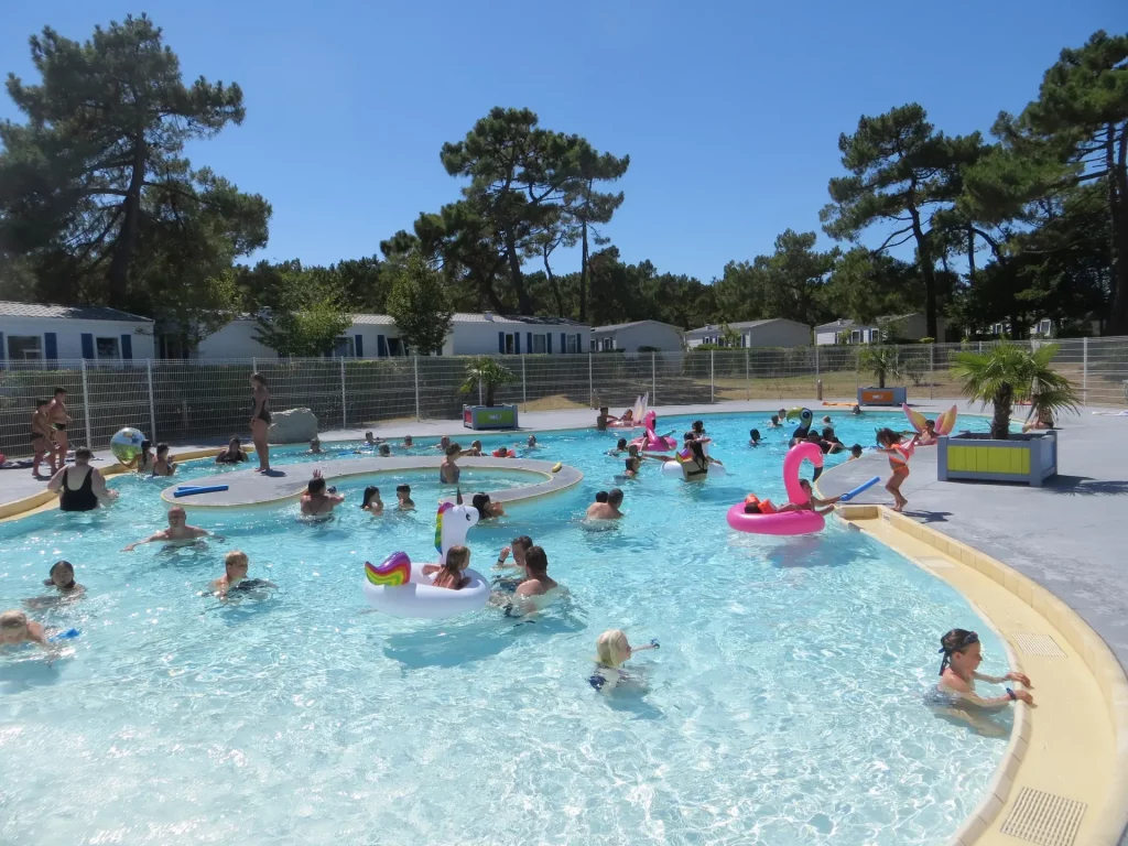 Enfants et adultes s'amusent dans la piscine extérieure.