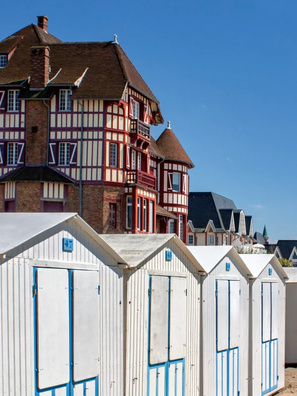 Maisons colorées et cabines de plage sur le sable.