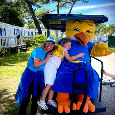 Enfant et adulte posant avec une mascotte colorée.