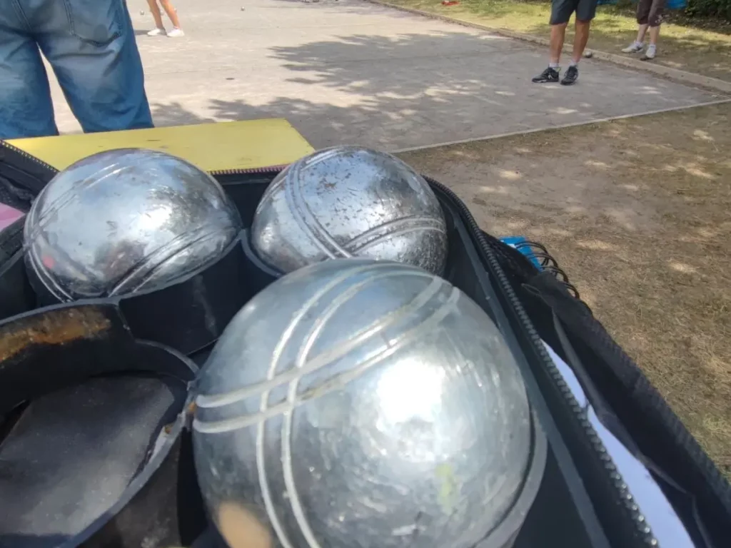 Boules de pétanque et joueurs sur le terrain.