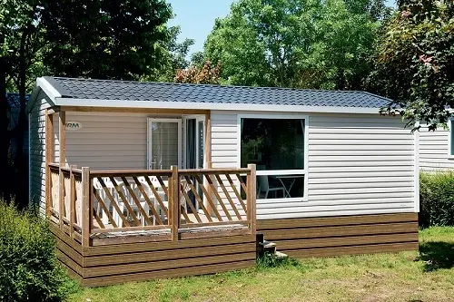 Mobil home avec terrasse dans un jardin.
