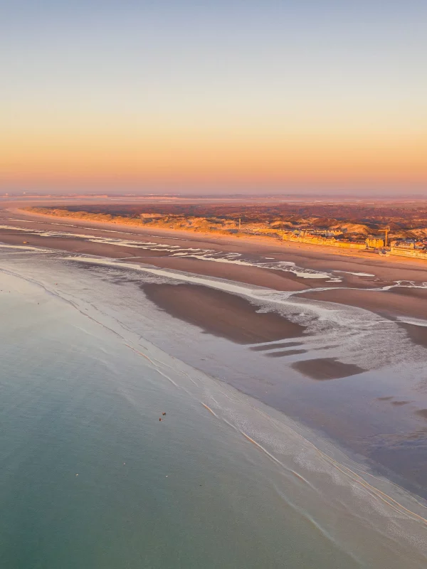 Plage au coucher de soleil avec eau calme.