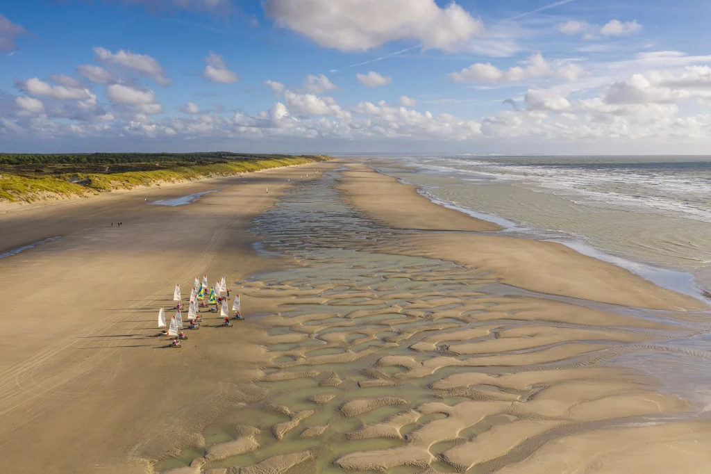 Plage avec voiliers et ciel nuageux.