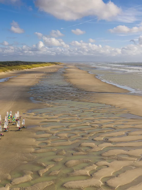 Plage avec voiliers et ciel nuageux.