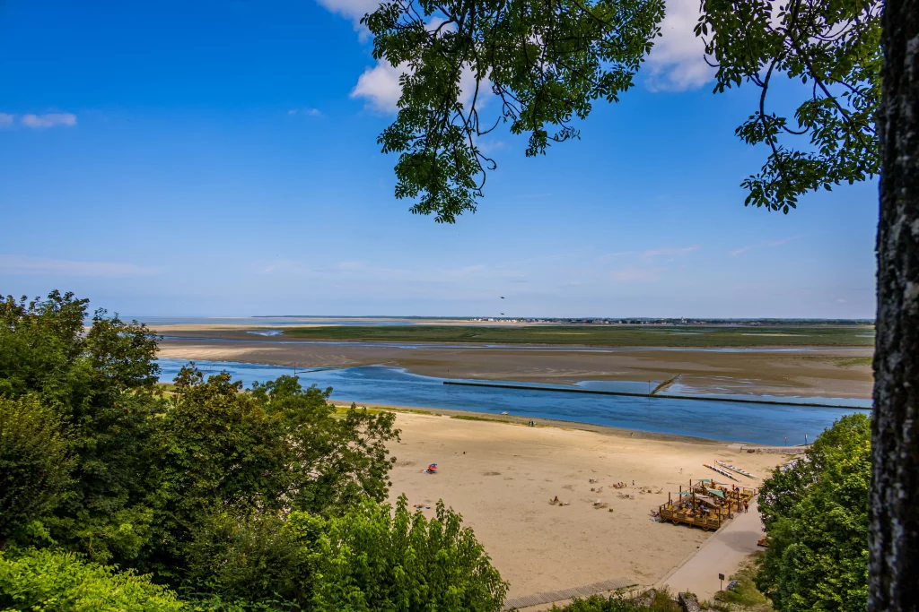 Plage et estuaire sous un ciel bleu.