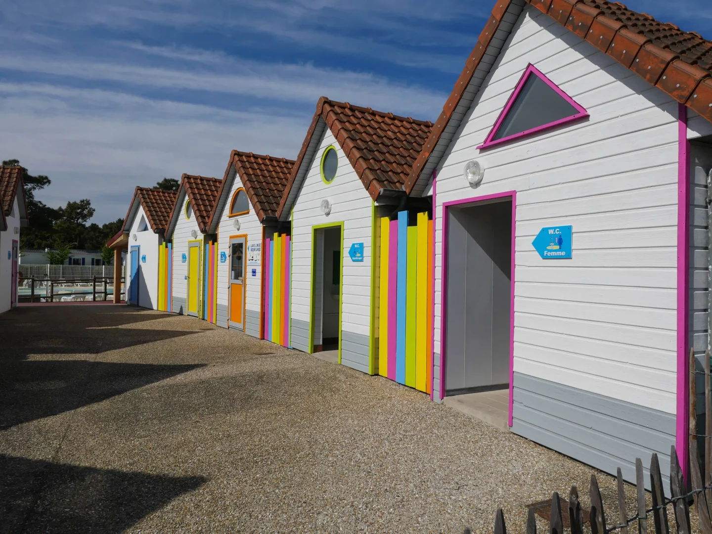 Cabines colorées près d'une plage ensoleillée.