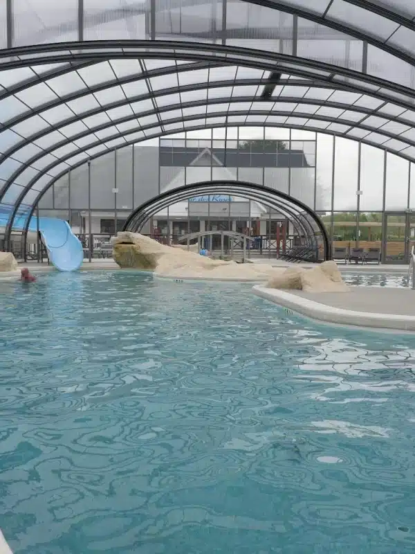 Piscine intérieure avec toboggan et sièges.