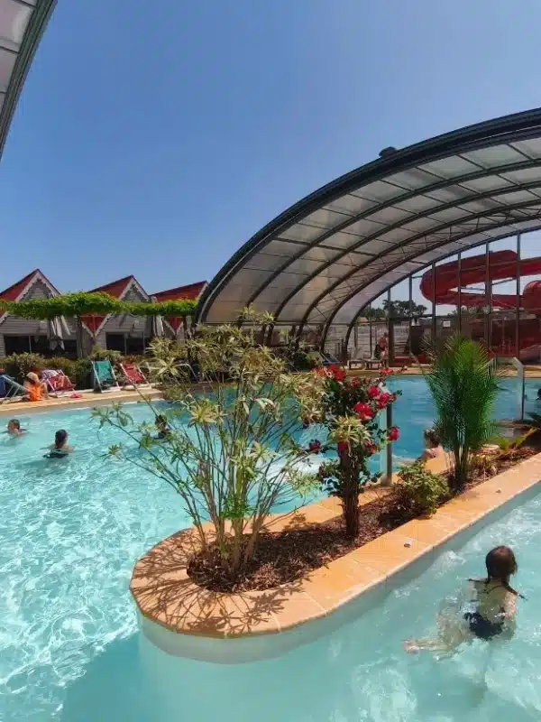 Piscine intérieure avec des nageurs et toboggans.